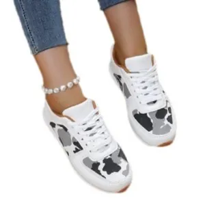 Women's white sneakers featuring cow print pattern and lace-up design for casual wear