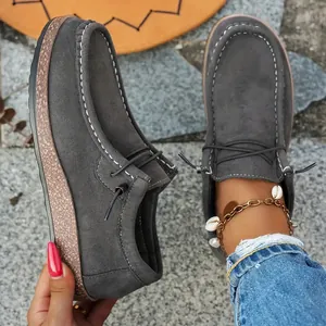 Detailed view of grey suede loafers with contrast stitching and thick cork soles.