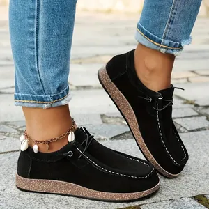 Close-up of black ethnic loafers with white stitching and platform wood sole