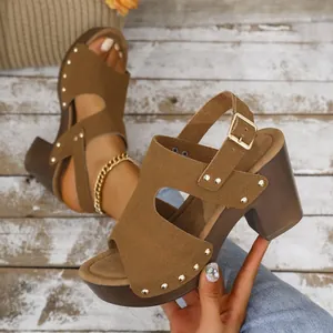 Detailopname van bruine sandalen met blokhak, gouden klinknagels en gespsluiting