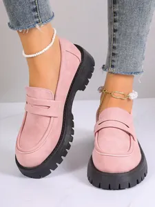 Close-up of pink suede platform loafers with chunky black soles on model's feet
