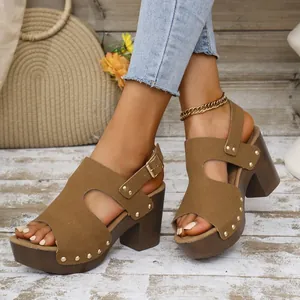 Detail van bruine sandalen met blokhak, klinknagels en hielbandje