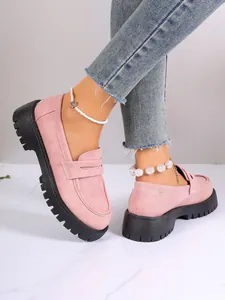 Detailed view of pink suede platform loafers featuring chunky black serrated soles and denim.