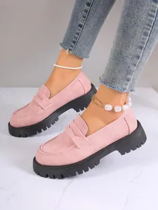 Side close-up view of stylish pink suede loafers featuring chunky black lug soles on a model