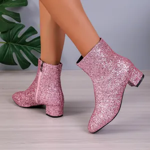 Close-up of stylish pink glitter ankle boots with chunky heels on model.