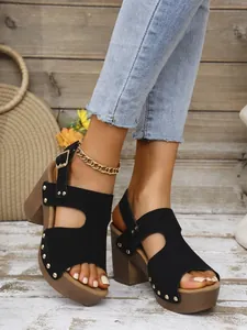 Detailopname van zwarte platform sandalen met studs, grove blokhakken en een enkelbandje