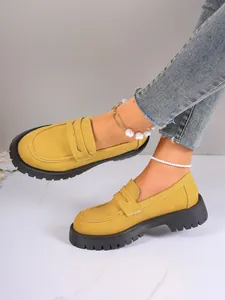 Close-up of yellow platform loafers featuring thick black soles and suede finish