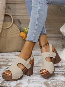 Detailopname van beige sandalen met blokhak, klinknagels en verstelbare hielbandjes