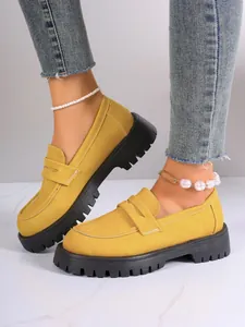 Close-up of stylish yellow platform loafers with thick black soles for a chic look.