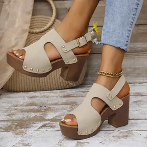 Detailopname van stijlvolle beige sandalen met blokhak, klinknagels en verstelbaar riempje.