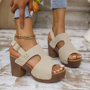 Detailopname van beige sandalen met blokhak, klinknagels en verstelbaar enkelbandje