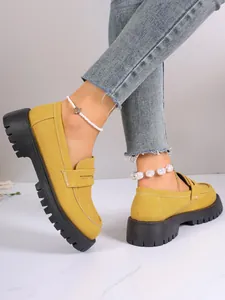 Side view detail of stylish yellow platform loafers featuring thick black lug soles