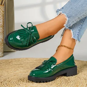 Detailed macro shot of stylish green patent leather loafers featuring a decorative bow and tassel