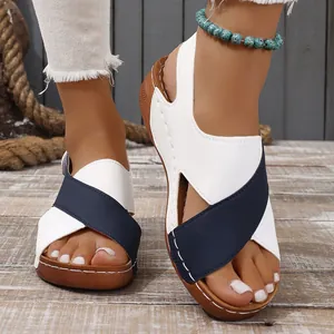 Close-up of women's white and blue cross-strap wedge sandals on a rustic wooden floor