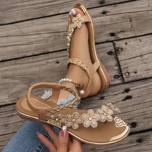 Detailed macro view of women's flat sandals featuring elegant rhinestone flower decorations