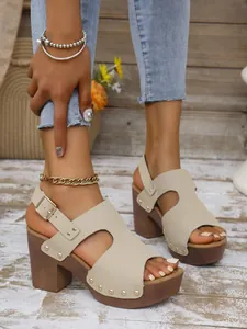 Detail van beige sandalen met dikke hak, studs, plateauzool en hielbandje