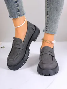 Close-up of grey women's platform loafers with thick lug soles and stylish anklets.