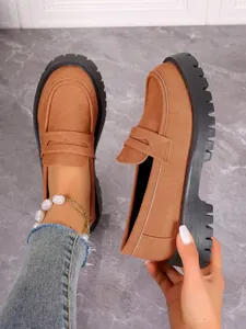 Macro view of brown suede loafers with chunky black soles and thick heels for women.
