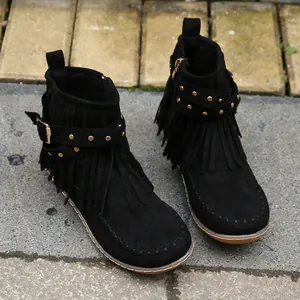 Detalle de botines negros con flecos, remaches dorados y hebilla decorativa
