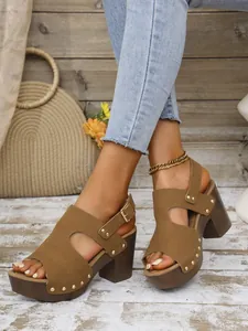 Detailopname van bruine platformsandalen met klinknagels en een dikke hoge hak