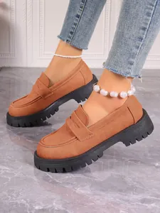 Detailed view of women's brown suede platform loafers with chunky lug soles and slip-on style