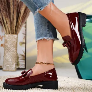 Close-up of wine red patent leather loafers with bow detail and chunky sole