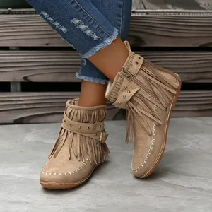Vista detallada de botines de ante beige con flecos, correas con remaches y cremallera lateral