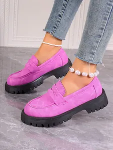 Detail of bright pink platform loafers with thick black lug soles and suede texture