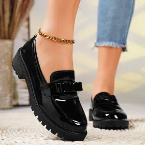 Close-up of stylish black patent leather loafers with chunky sole and bow detail