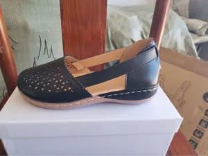 Detaillierte Seitenansicht schwarzer Keilsandalen für Damen mit hohlgearbeitetem Muster