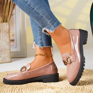 Detailed view of pink patent leather loafers featuring a gold buckle and thick black sole