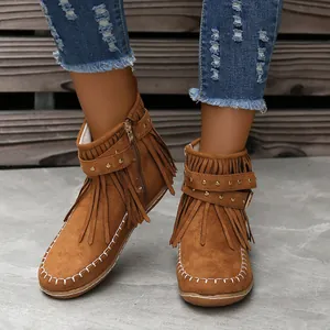 Detalle de botines de ante marrón con flecos remaches metálicos y costuras blancas