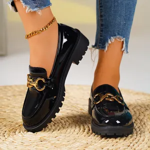 Detailed view of French style black patent leather loafers with elegant gold chain buckle