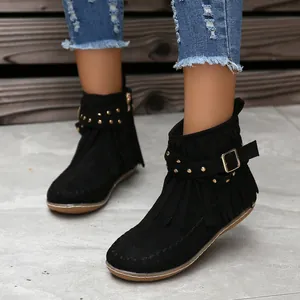 Primer plano de botines negros de ante con flecos y tachuelas doradas decorativas