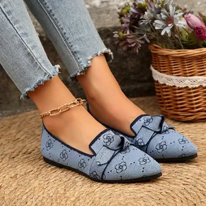 Détail de ballerines bleues en maille à bout pointu avec nœud et motif floral sur tapis