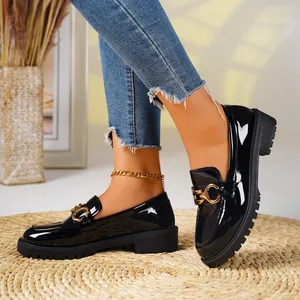 Elegant black patent leather chunky loafers featuring gold horsebit detail on a woven mat.