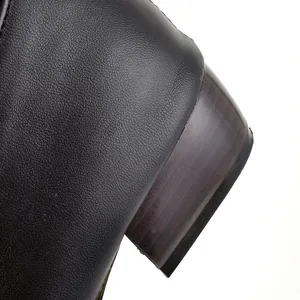Detail view showing the textured black leather and wood-grain heel of the fashion boot.
