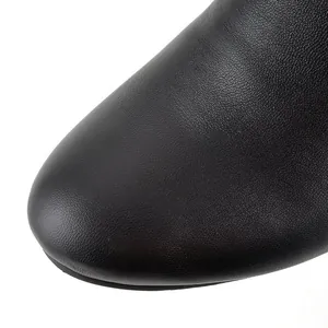 Macro view showing the smooth black leather texture and round toe of women's boots.
