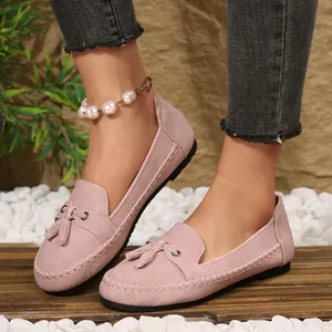 Detail view of pink suede loafers featuring decorative tassels and slip-on design