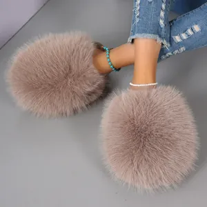 Close-up of oversized fluffy mauve fur slippers worn with blue distressed jeans.