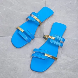 Detailed macro view of stylish blue flat sandals featuring elegant gold metallic strap accents