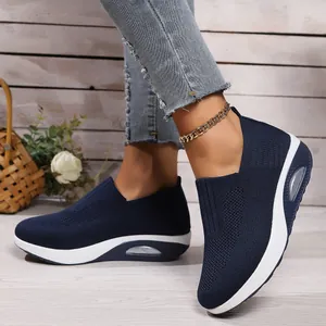 Close-up view of navy blue fly-knit rocker sneakers featuring white air cushion wedge soles.