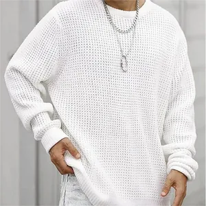 Gros plan sur la texture d'un pull blanc en maille ajourée avec coupe ample et col rond.