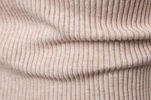 Dettaglio macro della trama del tessuto a maglia a coste su un maglione beige da uomo