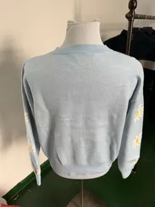 Back view of light blue knitted sweater with daisy pattern sleeves on a mannequin
