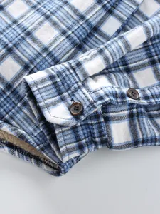Macro view of blue plaid shirt cuff showing brown buttons and warm white fleece lining