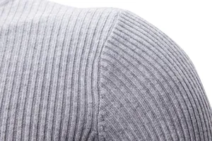 Primo piano della cucitura della spalla di un maglione grigio a costine in maglia