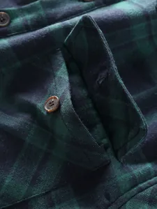 Macro shot of green and black plaid shirt fabric texture with pocket flap and button