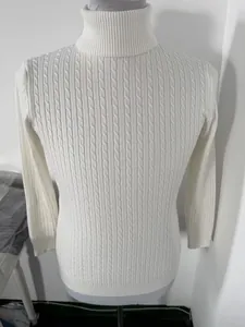 Close-up detail of a men's white cable-knit turtleneck sweater showing texture.