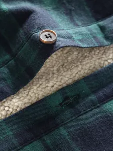 Macro detail of men's green plaid flannel shirt featuring warm white fleece lining and button